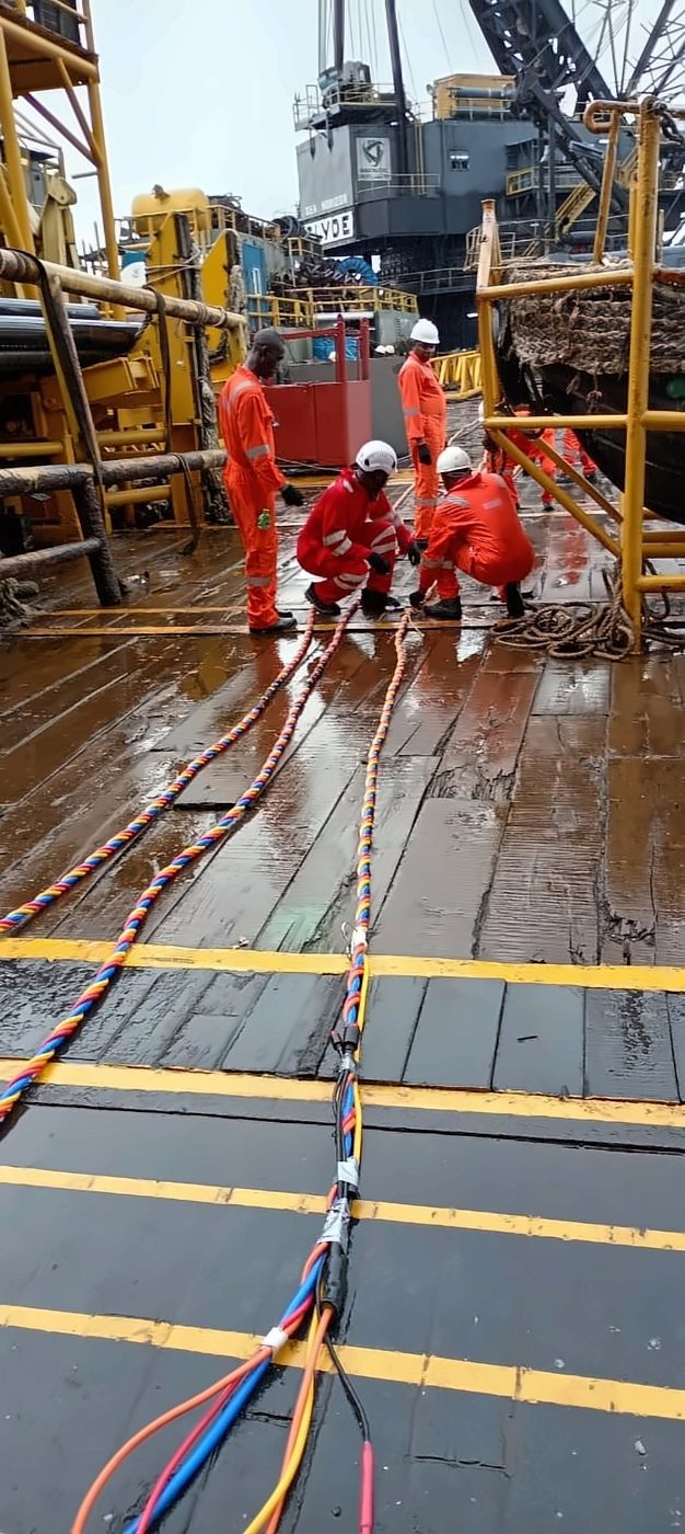 Dive Marine crew handling dive umbilicals during deck operations on a work barge